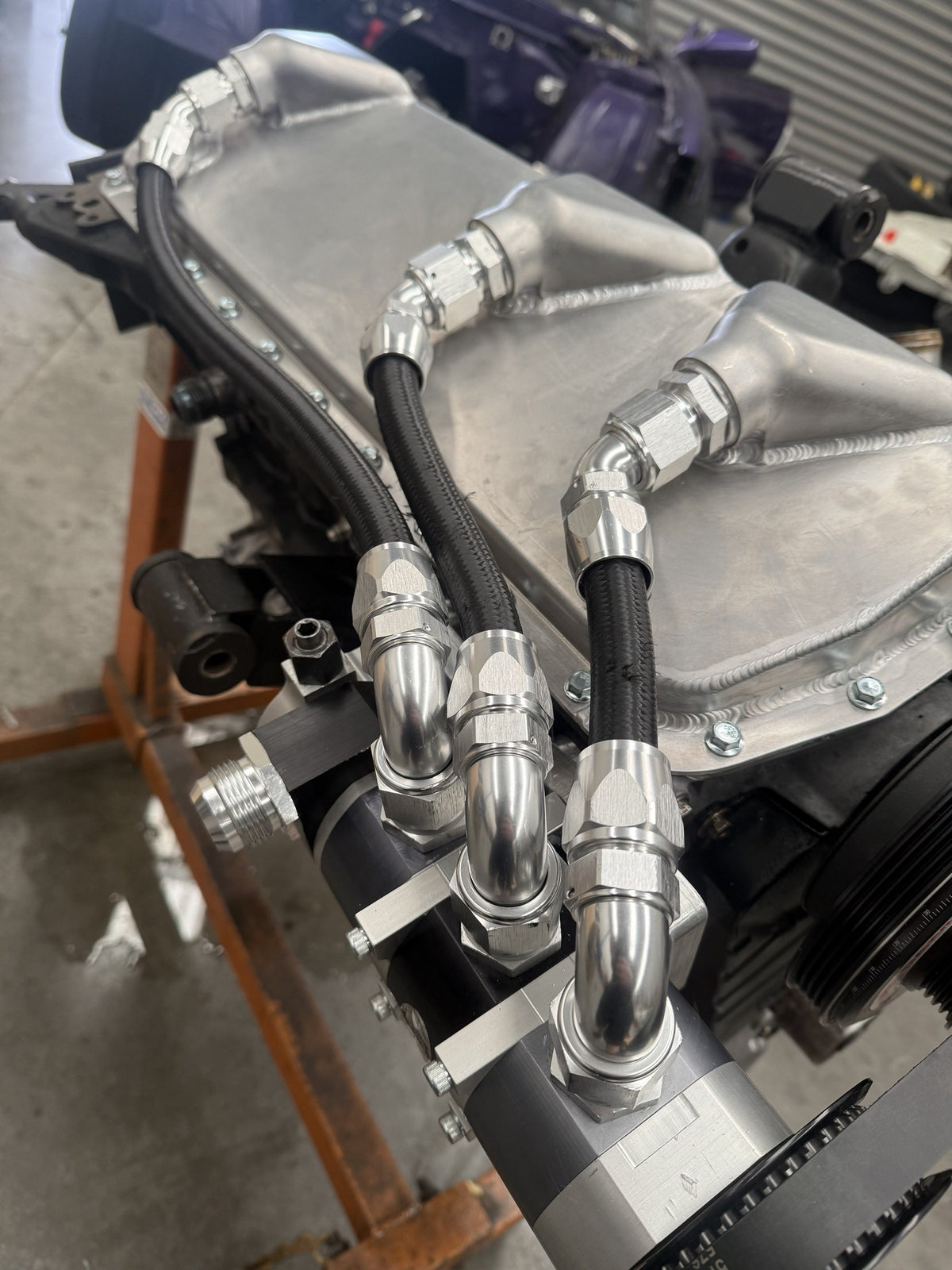 Close-up of the RB dry sump pan's three scavenge outlets plumbed with braided hose to the dry sump pump